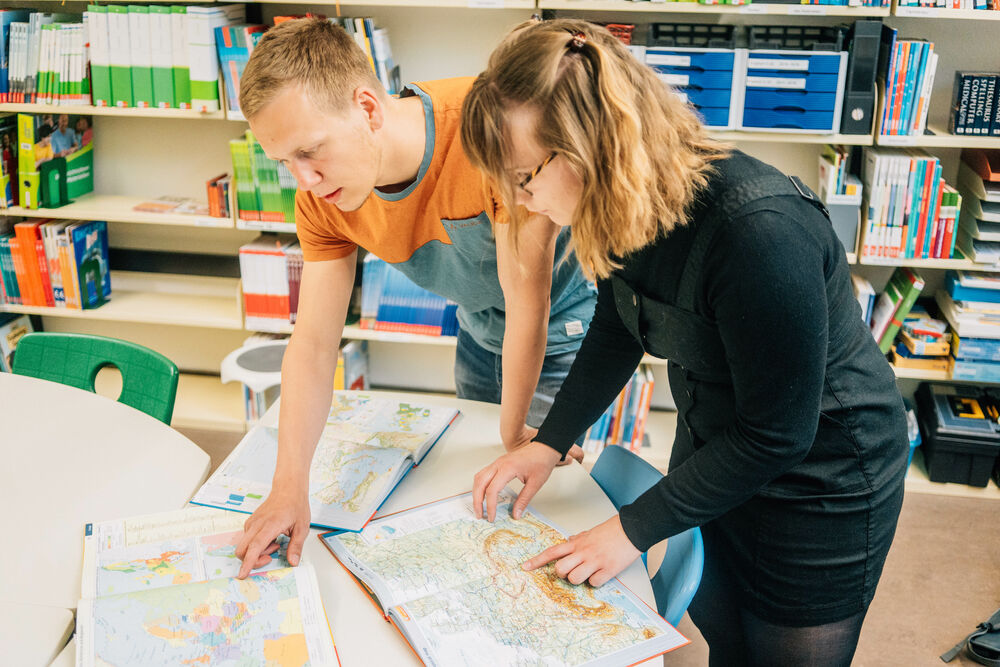 Two student teachers looking at textbooks in a school classroom