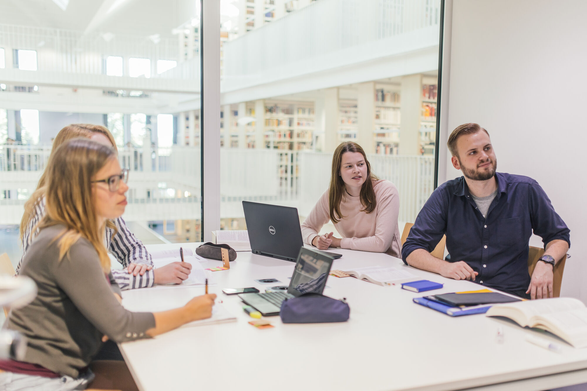 Lernsituation in der Bereichsbibliothek: Vier Personen sitzen in einem Gruppenraum an ihren Notebooks.