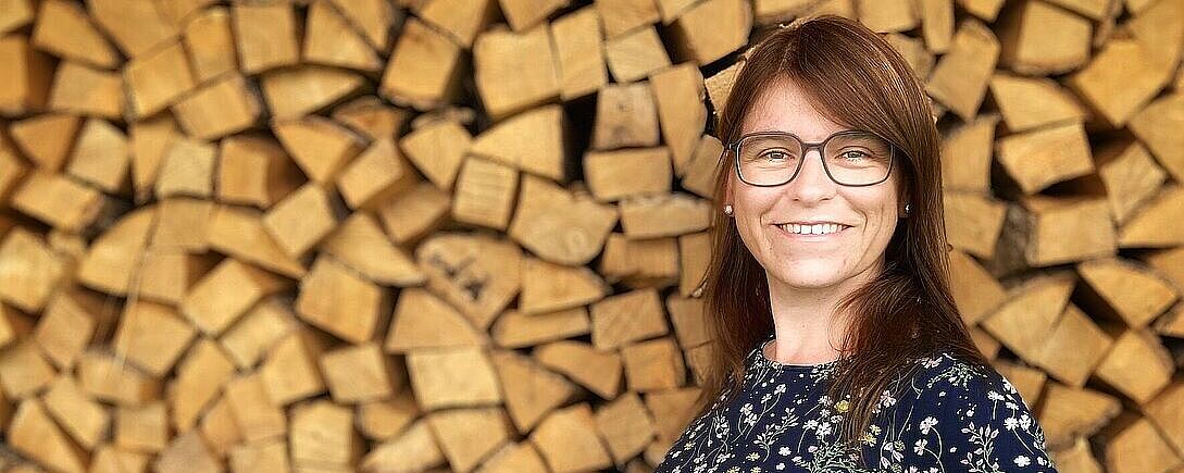 Portraitfoto von Anne Seidlitz vor gestapelten Holzscheiden