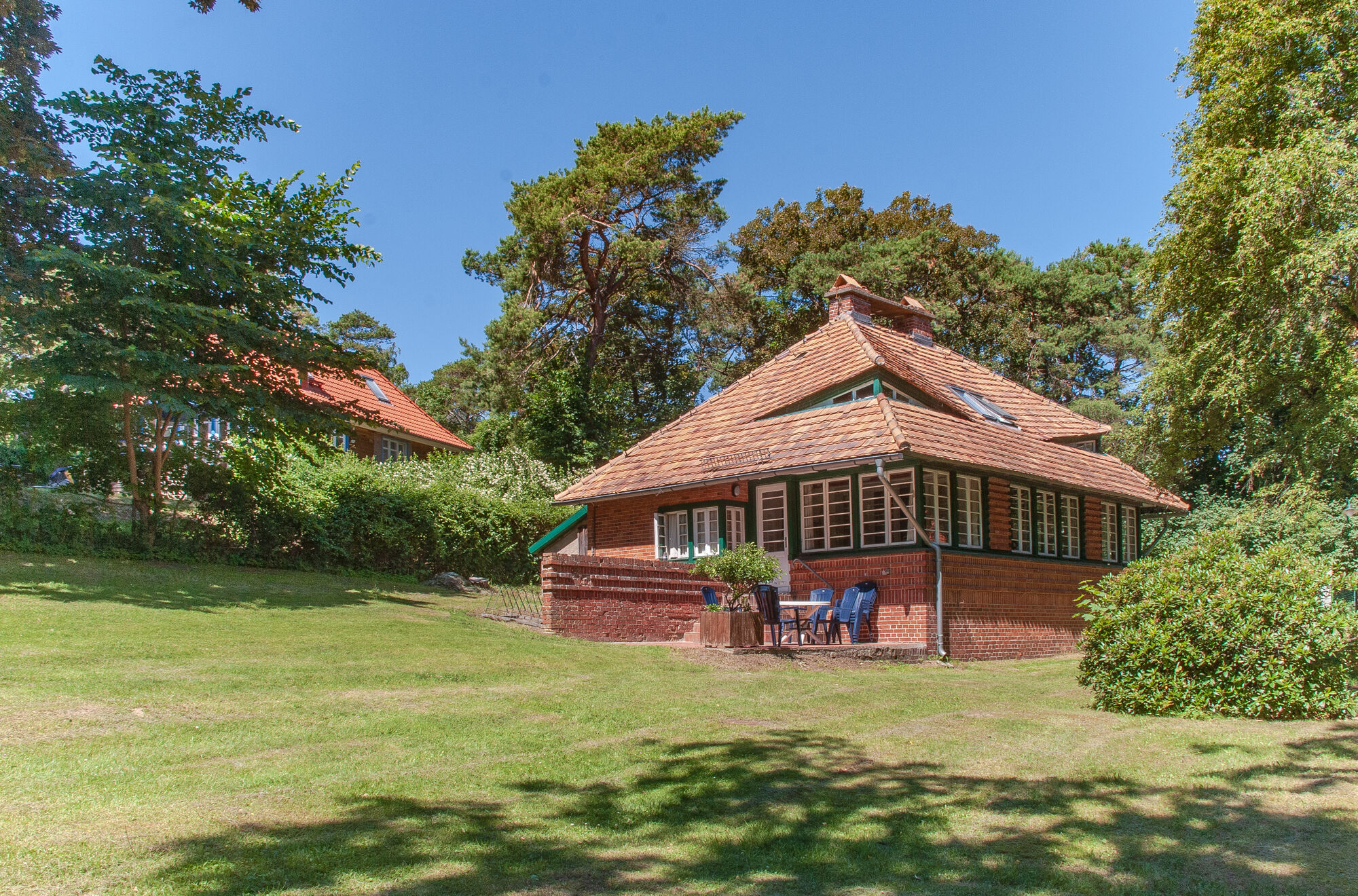 Auf dem Bild ist das das Doktorandenhaus in der Biologischen Station auf Hiddensee zu sehen. Es steht auf einer Wiese, rundherum stehen Bäume. 