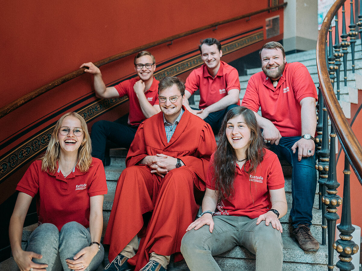 Guides der Kustodie sitzen auf der Treppe im Alten Audimax.