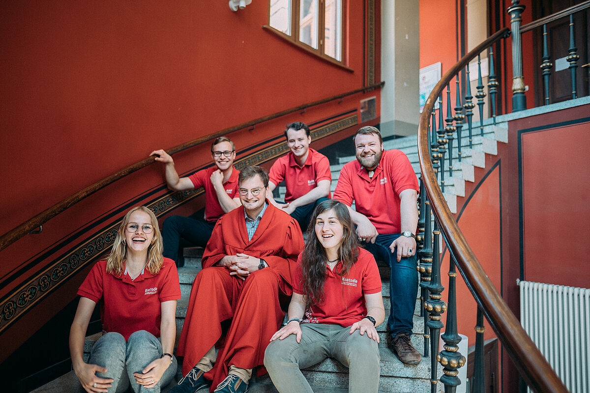 Guides der Kustodie sitzen auf der Treppe im Alten Audimax.