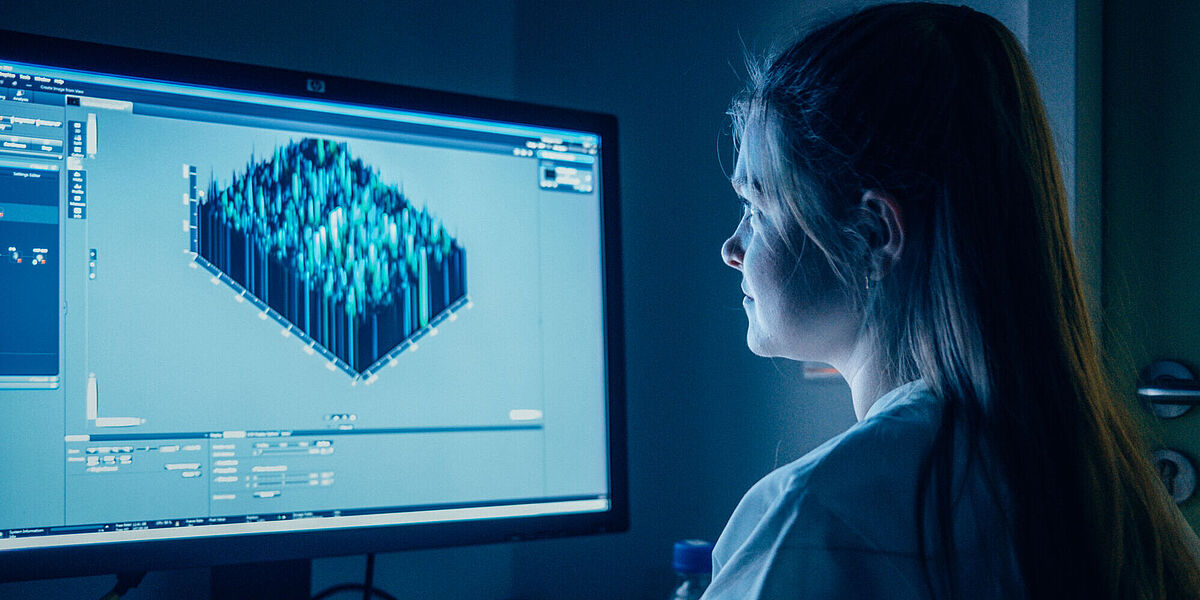 Eine Mitarbeitende der Universität Greifswald sitzt in einem Labor vor einem Monitor