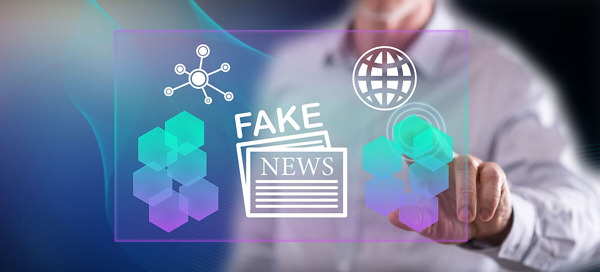 Ein Mann berührt ein Fake-News-Konzept an einem Bildschirm.
