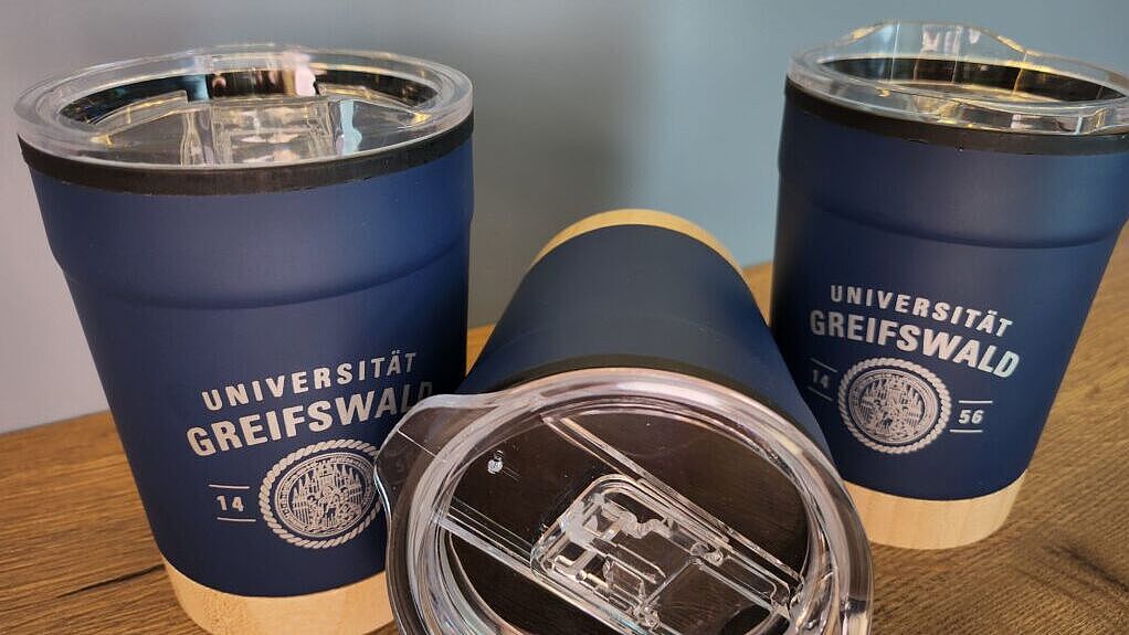 Auf dem Bild sind drei Trinkbecher mit dem Schriftzu Universität Greifswald und dem Siegel der Universität zu sehen.