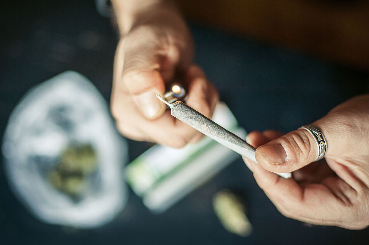 Jemand hält einen Joint. Mit der anderen Hand wird er angezündet.