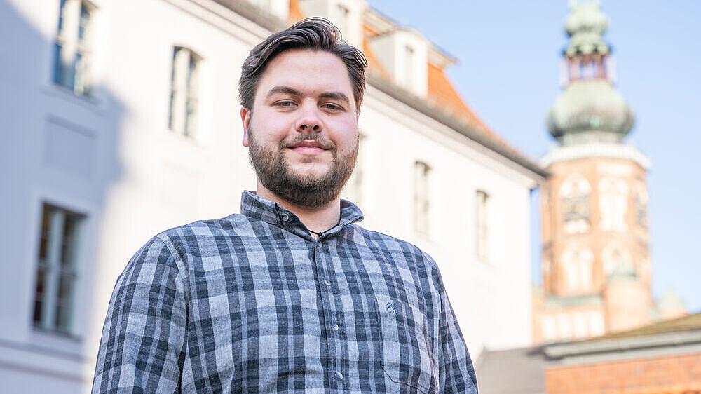 Portät von Franz Ludwig, Mitarbeiter in der Zentralen Studienberatung. Er steht auf dem Innhof der Universität Greifswald. 