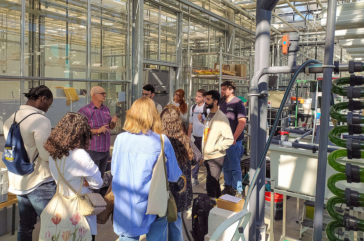 Auf dem Bild ist eine Gruppe beim Besuch der Aquaponicanlage an der Universität Rostock während der Sommerschule SustainMV 2023 zu sehen. 