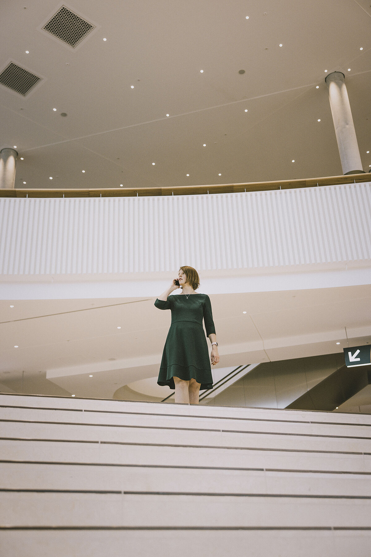 Dr. Anica Graf auf einer Treppe in einem Gebäude, telefonierend.